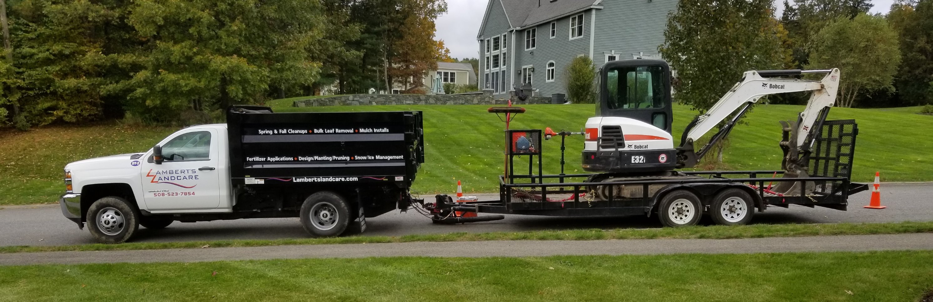 Lambert's Landcare branded truck and trailer with landscaping equipment